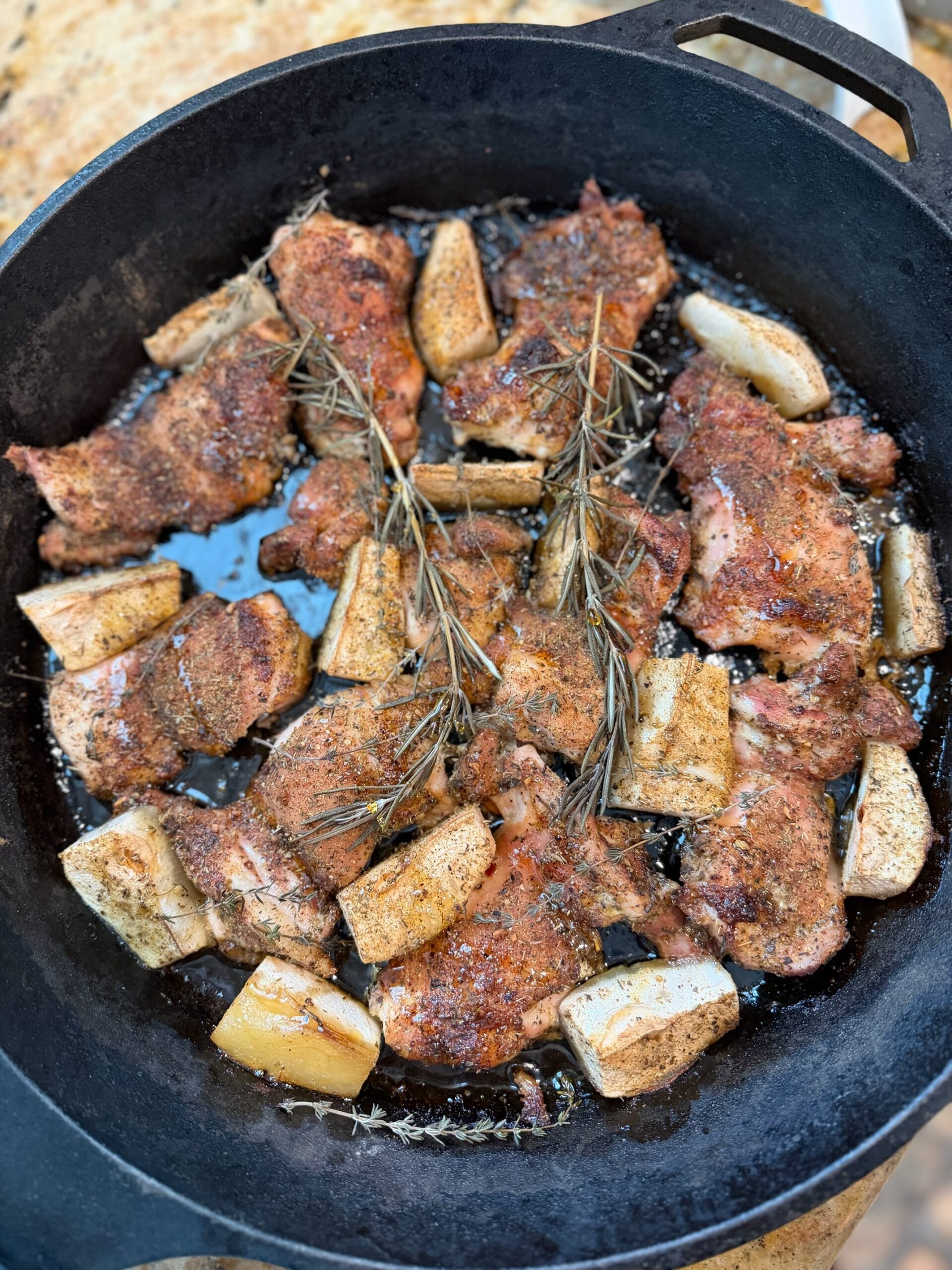Honey pear and herb roasted chicken thighs in a cast iron skillet with caramelized pears and sprigs of fresh rosemary and thyme.
