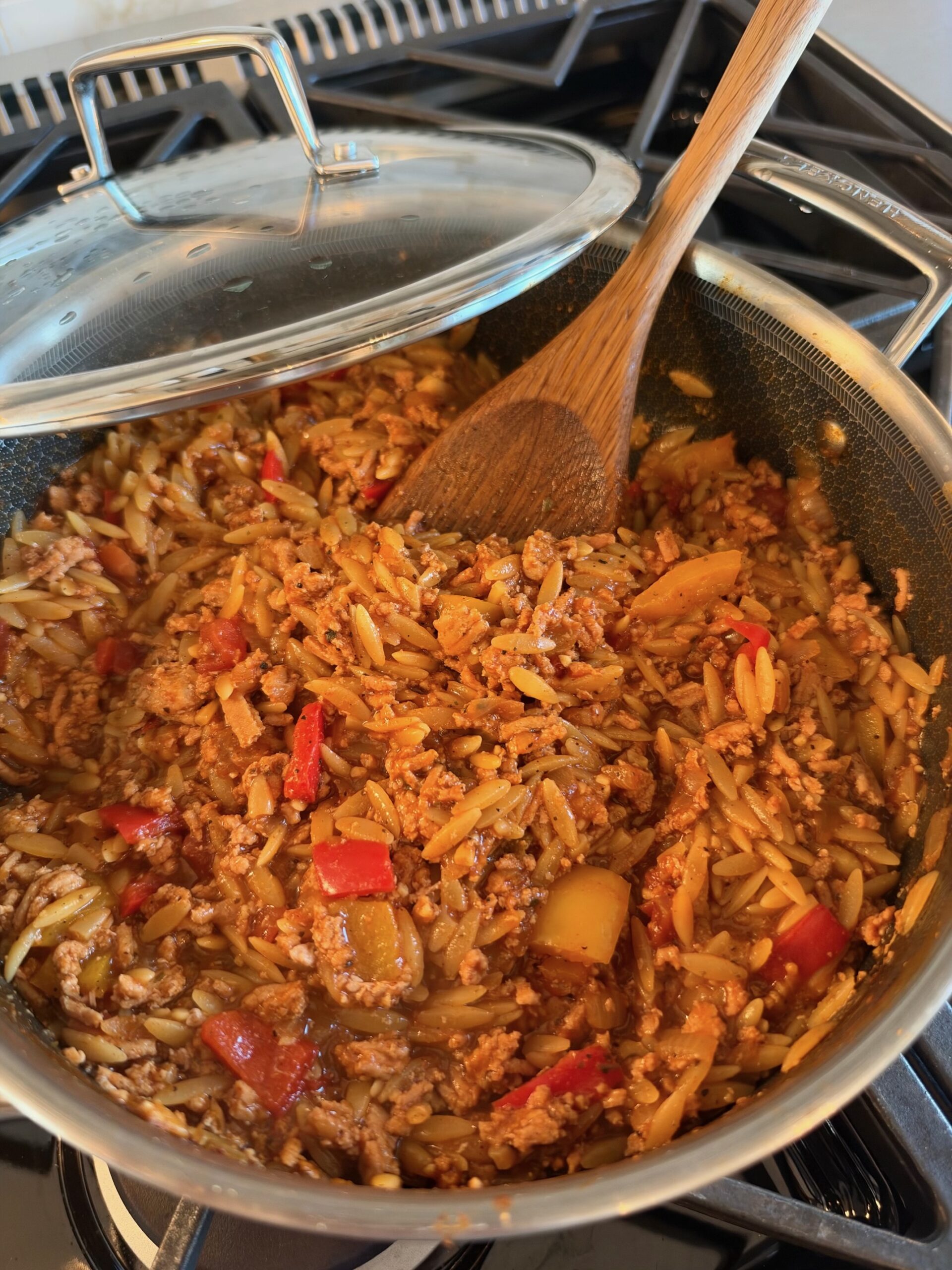 One-pot fajita ground turkey orzo with red and orange bell peppers in a large pot on the stovetop.