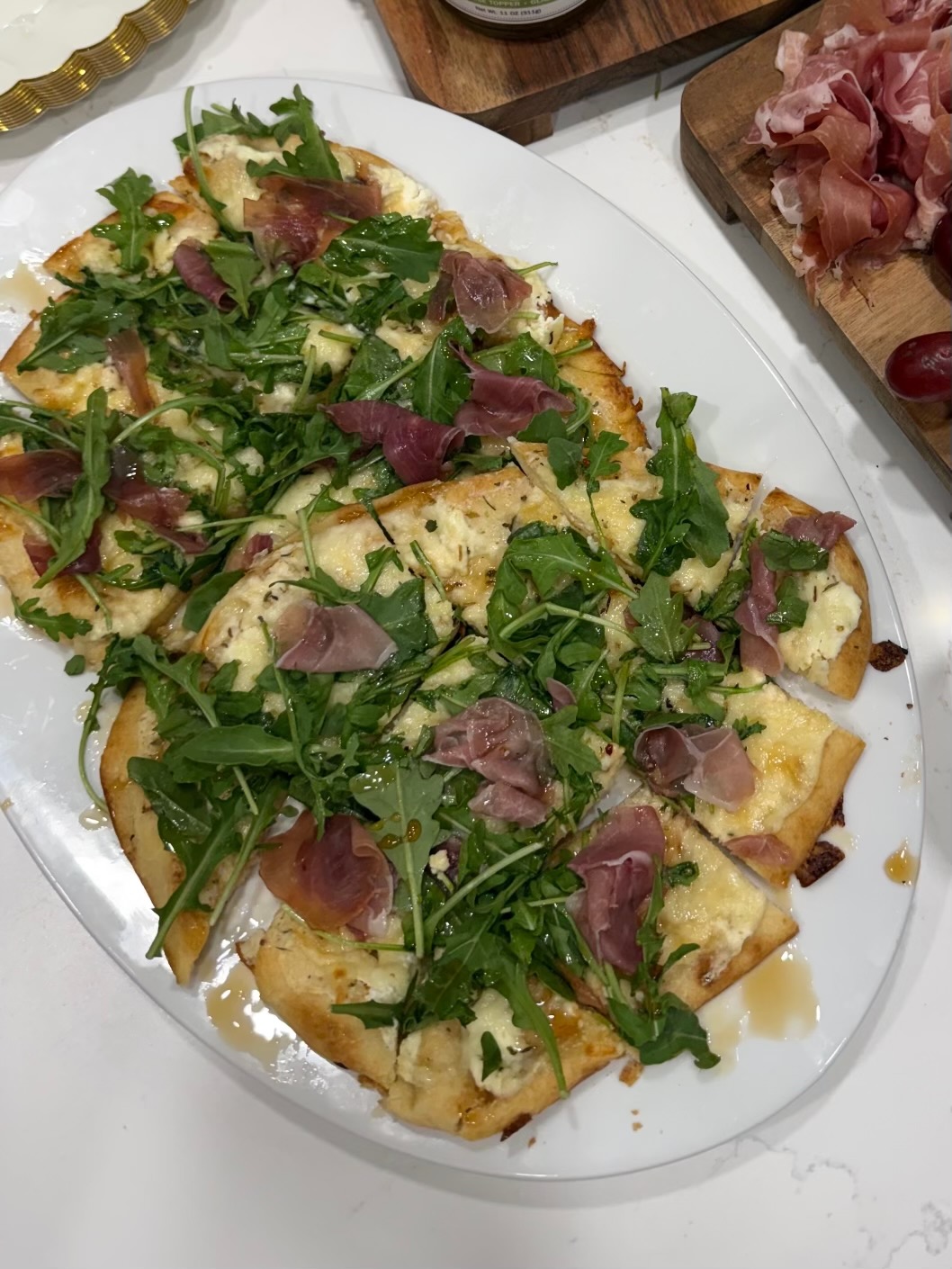 Prosciutto flatbread on toasted naan topped with melted cheese, pear jam, fresh arugula, torn prosciutto, and a drizzle of hot honey.